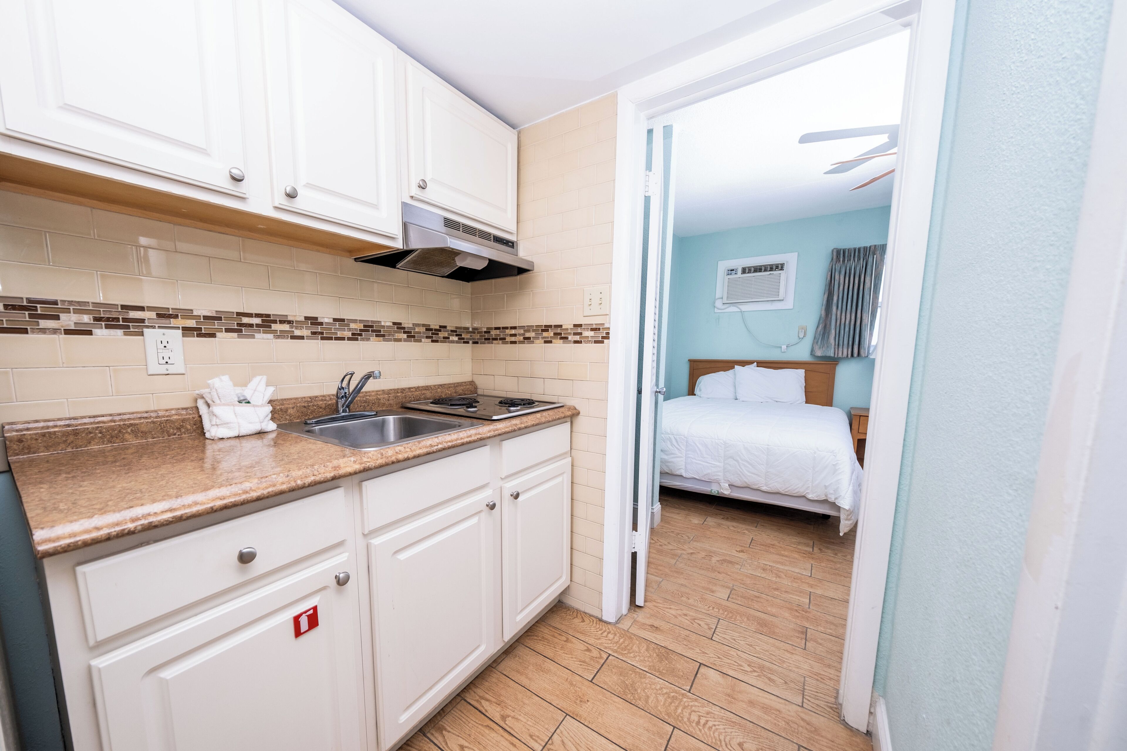Quarto de hotel pequeno com cozinha compacta, uma cama e banheiro.