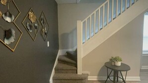A staircase with a beige handrail and carpeted steps leading to a landing.