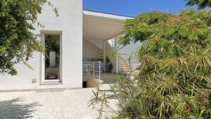 A modern building with a covered outdoor seating area and a large window overlooking the interior. - Ammarèa B&B (Ugento)