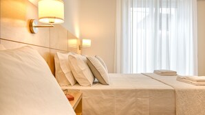 A hotel room with a large bed, two bedside tables, and a window with sheer curtains. - Ammarèa B&B (Ugento)