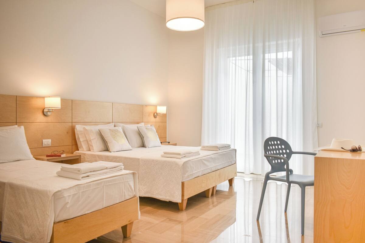 A hotel room with two beds, a desk, and a chair.