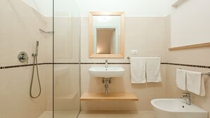 A modern bathroom with a glass shower enclosure, a sink with a mirror above it, and a toilet. - Ammarèa B&B (Ugento)