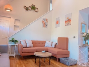 Uma sala de estar moderna com um sofá seccional, uma mesa de centro redonda e uma escada que leva a outro andar.