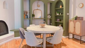 A dining area with a round table, four grey chairs, a wooden cabinet, and a green accent wall. - Tranquil Cape getaway 4BD 2BA with AC, Family and Pet Friendly!  (Mashpee)
