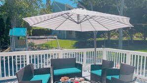 A deck with wicker furniture and a table set for a meal, surrounded by a white railing. - Tranquil Cape getaway 4BD 2BA with AC, Family and Pet Friendly!  (Mashpee)