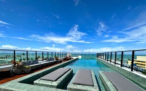 A rooftop infinity pool with lounge chairs and potted plants, overlooking a clear blue ocean. - SH Get One  (João Pessoa)