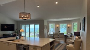 A spacious kitchen with a large island, a dining area with a view, and a living room with a TV and seating. - Enjoy nightly sunsets at this Beautiful Door County Waterfront Home (Sturgeon Bay)