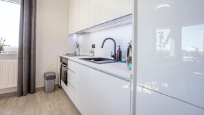 Moderni keittiö, jossa on valkoiset kaapit, musta hana ja ruostumattomasta teräksestä valmistettu pesuallas.