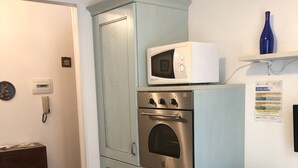 A compact kitchen with a microwave, oven, and a small cabinet. - Comfortable Apartment center Sarzana (Sarzana)