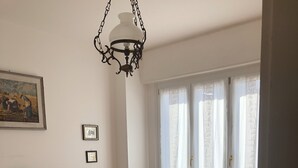 A bedroom with a bed, a chair, a dresser, a painting, and a window with curtains. - Comfortable Apartment center Sarzana (Sarzana)