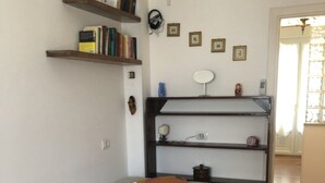 A neatly arranged bedroom with a bed, a shelf with books, a small table, and a wall clock. - Comfortable Apartment center Sarzana (Sarzana)
