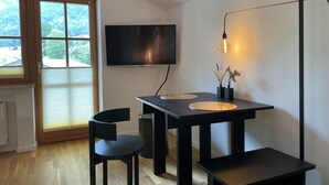 Un comedor moderno con una mesa, sillas, un televisor y una lámpara.