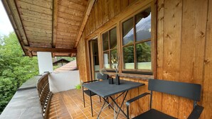 Una cabaña de madera con balcón, una mesa y dos sillas.