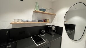 Una cocina moderna con encimera negra, estufa integrada y un estante de madera con diversos utensilios de cocina.