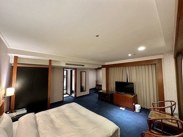 A hotel room with a bed, a television, a desk, and a chair. - SeekerHotel-Sanchong (New Taipei City)