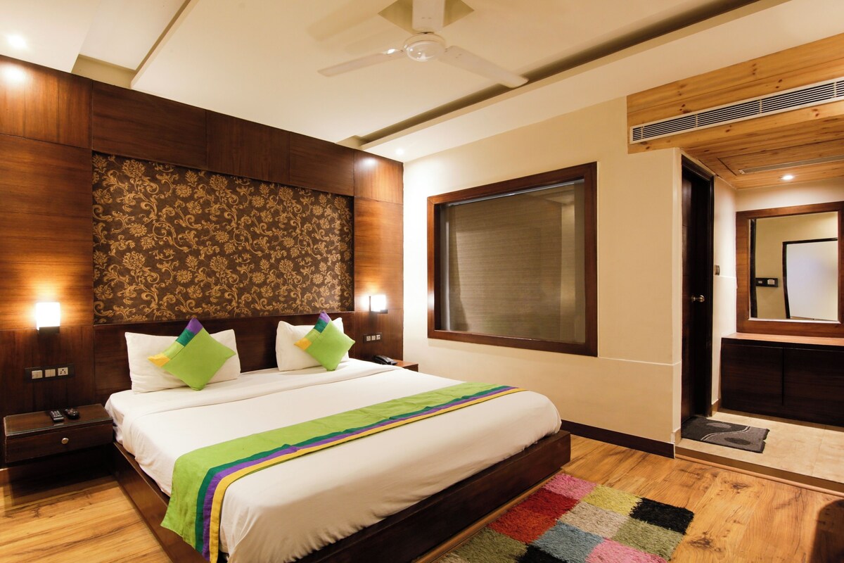 A hotel room with a large bed, wooden headboard, and a view of the outside.