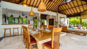 A spacious dining area with a wooden table set for six, surrounded by wooden chairs with red cushions. - Villa Alroda Sawah (Canggu)