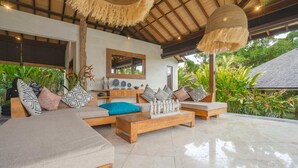 A spacious living area with a large sofa set, a coffee table, and a hanging light fixture. - Villa Alroda Sawah (Canggu)
