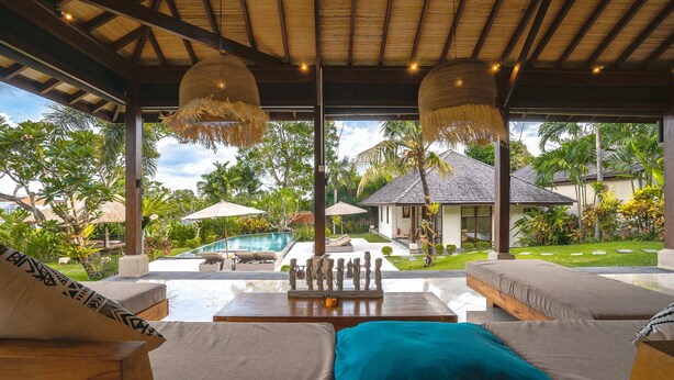 A covered outdoor seating area with lounge chairs and a thatched ceiling. - Villa Alroda Sawah (Canggu)