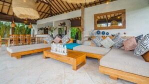 A spacious living area with a high ceiling, wooden furniture, and a variety of decorative pillows. - Villa Alroda Sawah (Canggu)