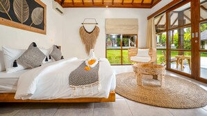 A bedroom with a bed, a chair, a large window, and a view of the outdoors. - Villa Alroda Sawah (Canggu)