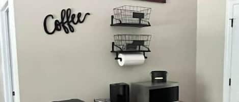 Una cocina con estación de café, refrigerador y microondas.