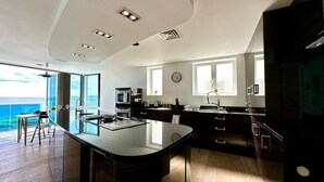 A modern kitchen with a central island, large windows, and a view of the ocean. - Stunning Panoramic Sea View Beach Location 2 bed (bournemouth)