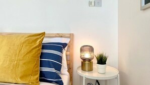 A neatly arranged bedroom with a bed, pillows, a bedside table with a lamp, and a small potted plant. - Stunning Panoramic Sea View Beach Location 2 bed (bournemouth)