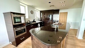 A modern kitchen with built-in ovens, a central island, and a large window. - Stunning Panoramic Sea View Beach Location 2 bed (bournemouth)