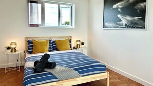 A bedroom with a bed, two bedside tables, a window, and a wall-mounted picture. - Incredible Panoramic Sea View 2 Bedroom Sleeps 4 WOW! (bournemouth)