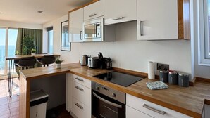 A modern kitchen with white cabinets, a wooden countertop, a built-in microwave, a toaster, and a coffee maker. - Incredible Panoramic Sea View 2 Bedroom Sleeps 4 WOW! (bournemouth)