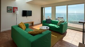 A modern living room with green sofas, a flat-screen TV, and a large skylight. - Incredible Panoramic Sea View 2 Bedroom Sleeps 4 WOW! (bournemouth)