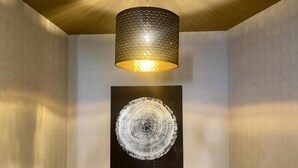 Interior moderno com teto texturizado, luminária pendente e uma peça de arte circular na parede.