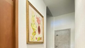 Um corredor com um quadro abstrato emoldurado, uma porta e uma escada.