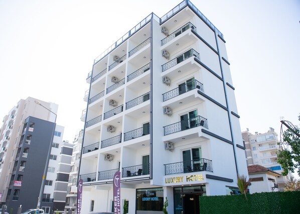 A multi-story hotel with balconies, air conditioning units, and a sign for 'LUXURY HOTEL'.