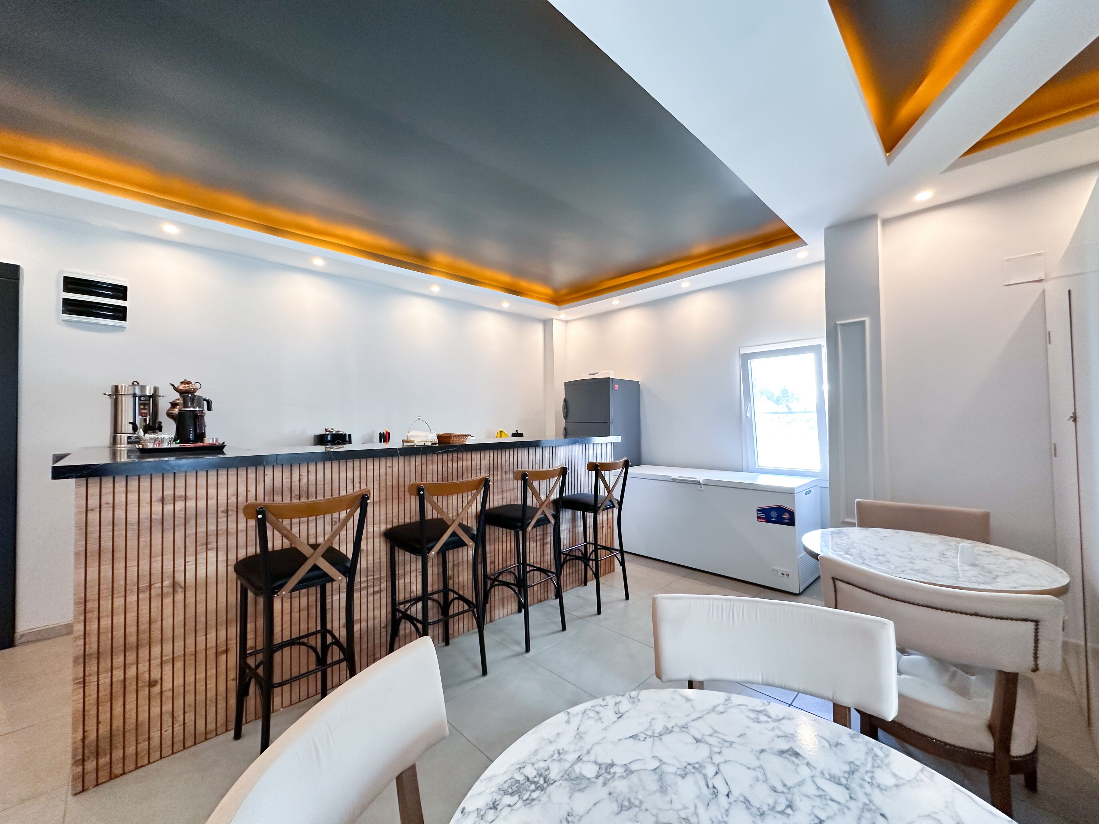 A modern kitchen with a bar area, bar stools, and a marble table.