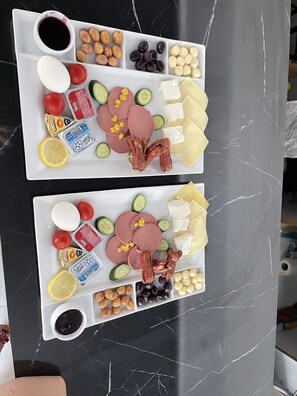 A marble-topped table with a variety of food items including cheese, cured meats, olives, and vegetables.