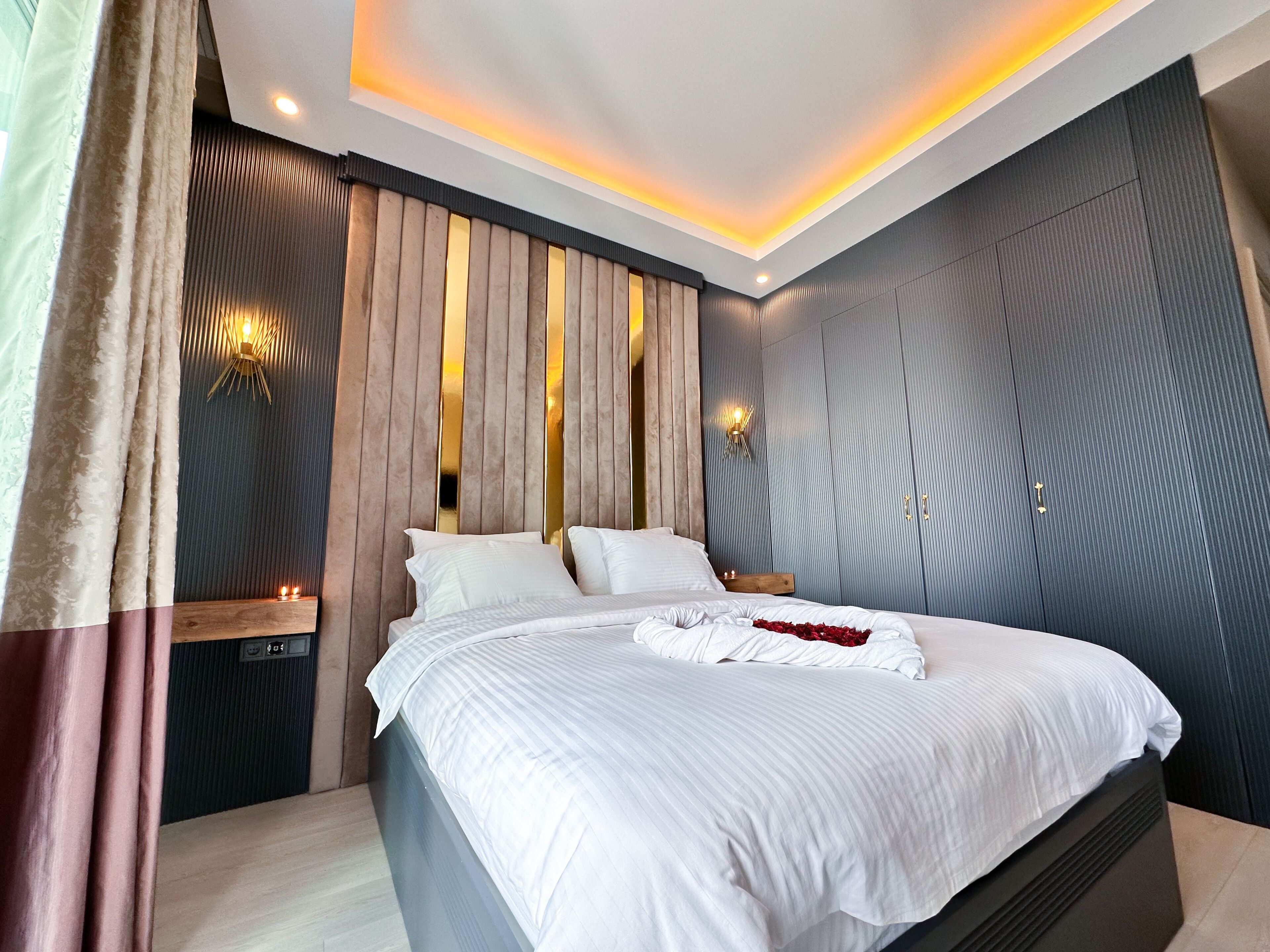 A modern bedroom with a large bed, a wooden headboard, and a wardrobe with a mirror.