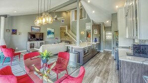 Una cocina moderna con una isla central, sillas tapizadas en rojo y una lámpara colgante.