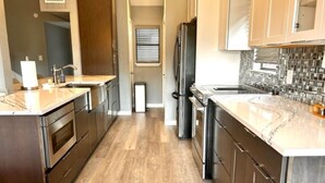 Una cocina moderna con electrodomésticos de acero inoxidable, armarios de madera y encimera de mármol.
