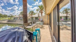 Un patio techado al aire libre con piscina, palmeras y vistas a otros edificios.
