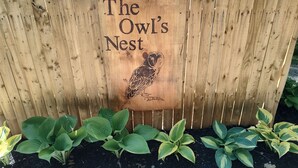 A wooden sign with "The Owl's Nest" and an owl engraving.