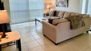 A living room with a beige sofa, a coffee table, a lamp, and a ceiling fan.