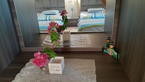 A bedroom with a bed, a bedside table, a mirror, and a decorative plant. - Authentic Lebanon - Charming, welcoming property in the heart of Magdouché (Maghdoucheh)