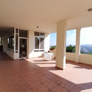 A spacious room with large windows, a tiled floor, and a table with a tablecloth. - Authentic Lebanon - Charming, welcoming property in the heart of Magdouché (Maghdoucheh)