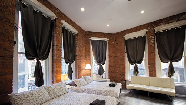 A hotel room with two beds, a sofa, and large windows with curtains. - JGSTAY - Koreatown (New York)