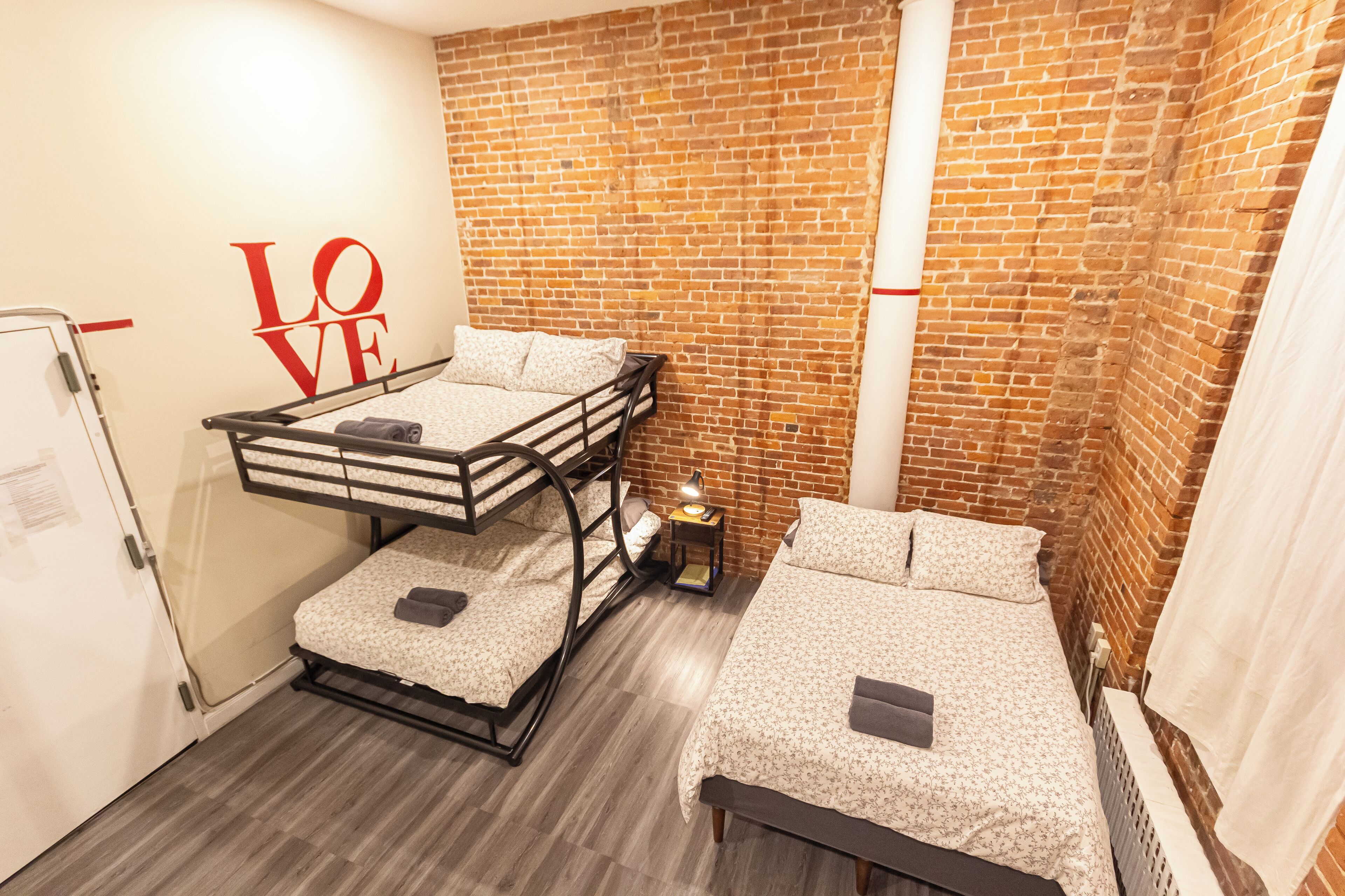Una habitación con una litera, una cama individual y una pared de ladrillo.