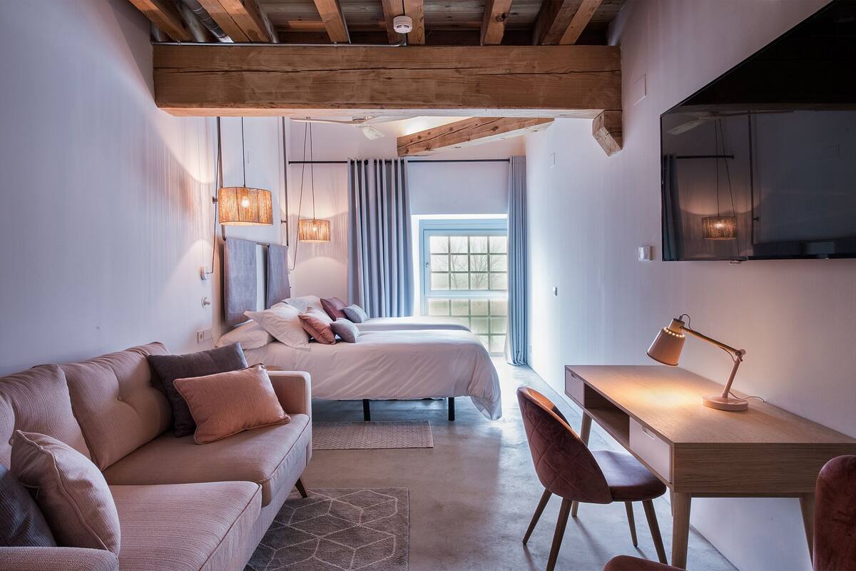 A modern bedroom with a wooden ceiling, a bed, a desk, and a chair.