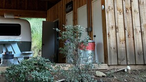 Una cabaña de madera con techo inclinado, un letrero de bienvenida y un pequeño porche con luces colgantes.