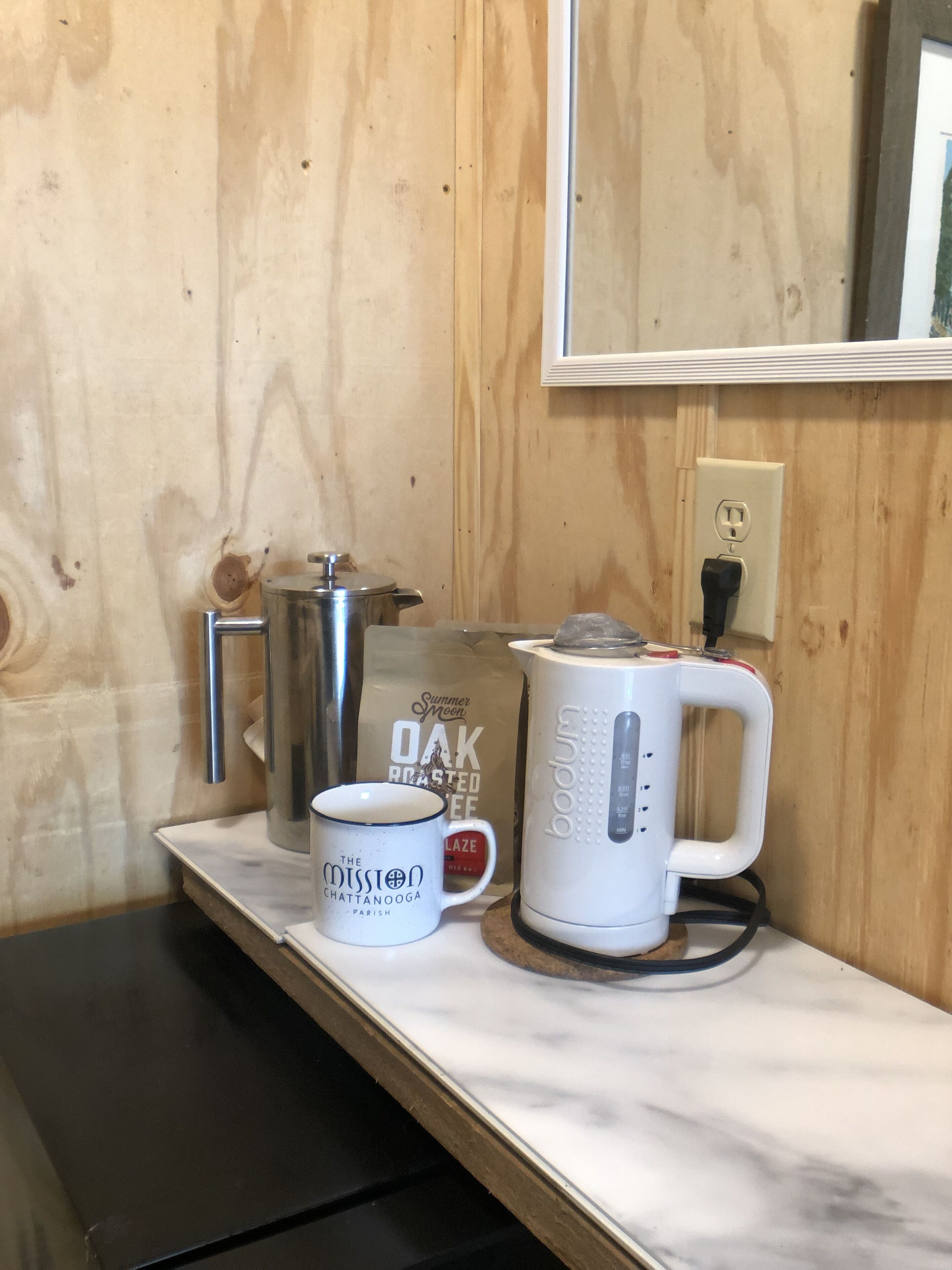 A kitchen counter with a coffee maker, a mug, and a bag of coffee beans.